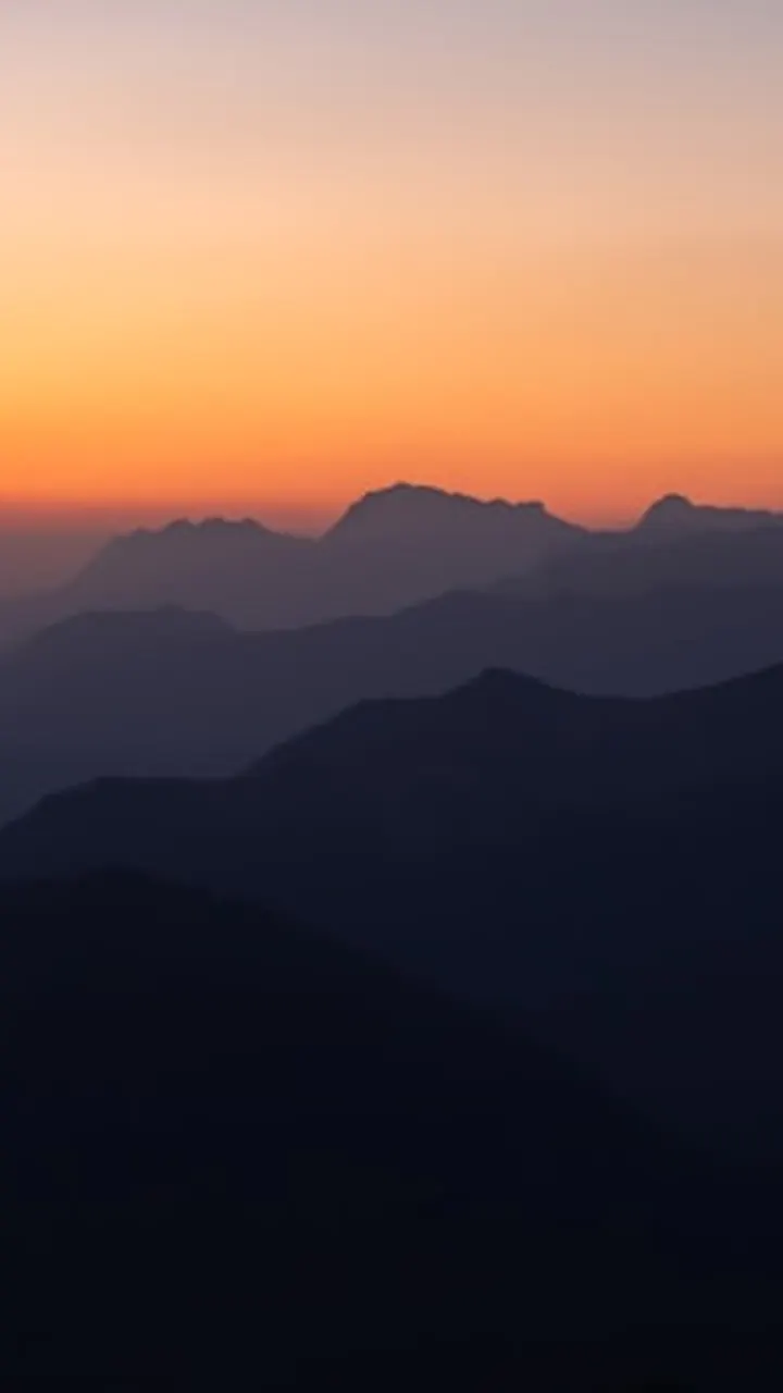 Pre-dawn mountain silhouettes under an orange horizon.