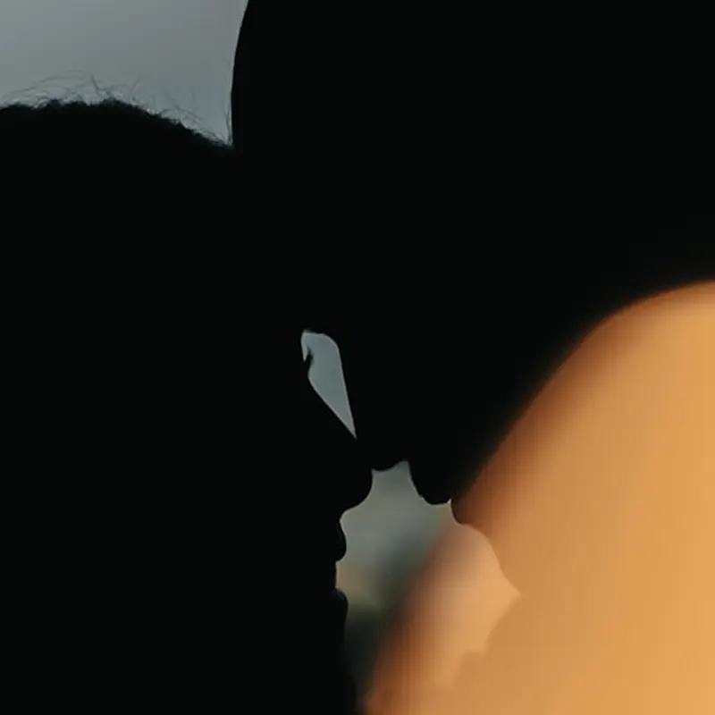 Couple in close silhouette at sunset, sharing a quiet intimate moment