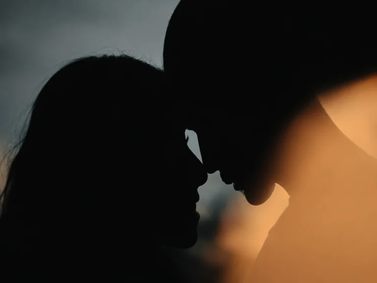 Silhouette of an intimate couple leaning close at sunset, representing romantic anticipation, emotional connection, and quiet intimacy
