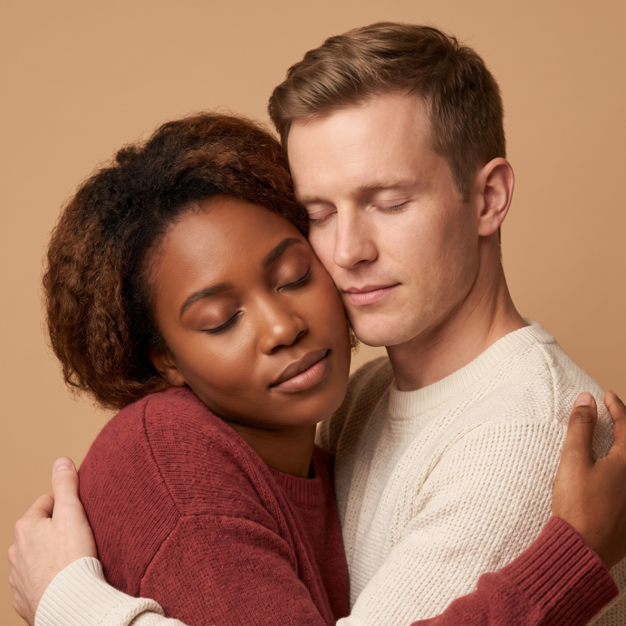 A close-up of a couple embracing cheek to cheek, eyes closed, warm and at ease.
